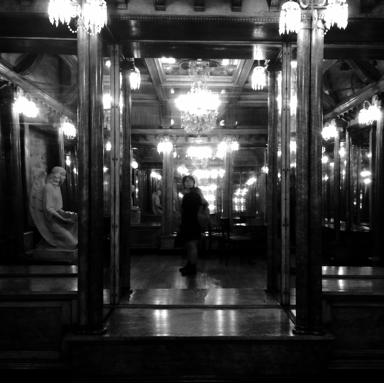 Self-portrait of me standing in the middle of an ornate, mirrored room, staring upwards at the far walls. There is a stone angel sitting on one side of the room, holding a bowl.